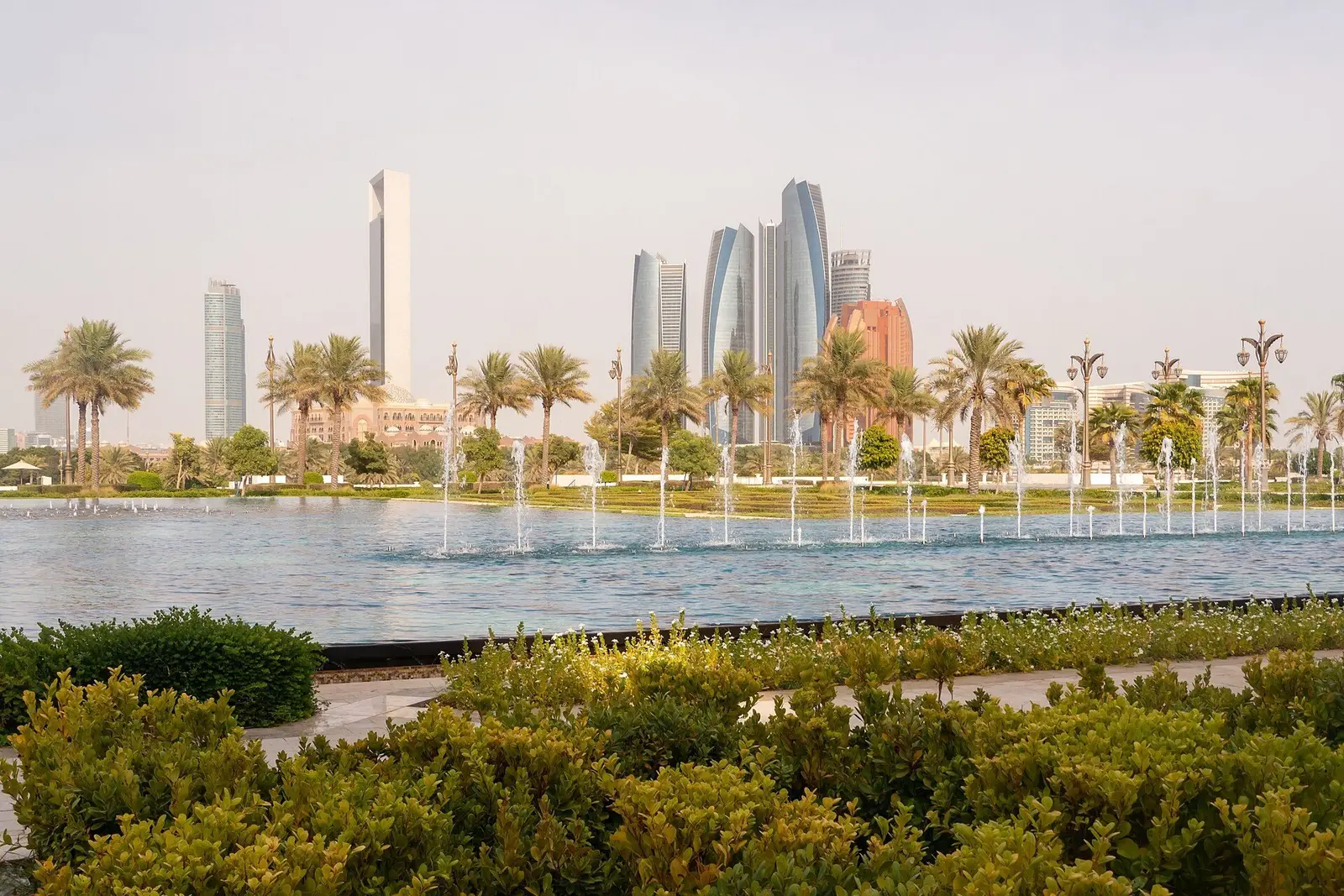 Fountains in Qasr Al Watan’s gardens with the Corniche towers behind