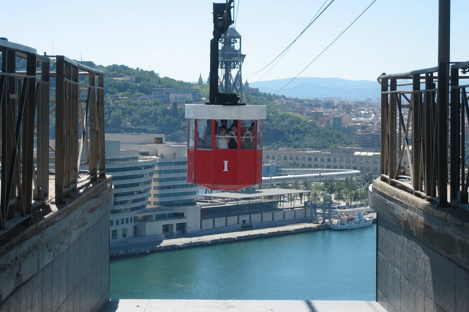 A red cable-car cabin hanging over Barcelona’s port