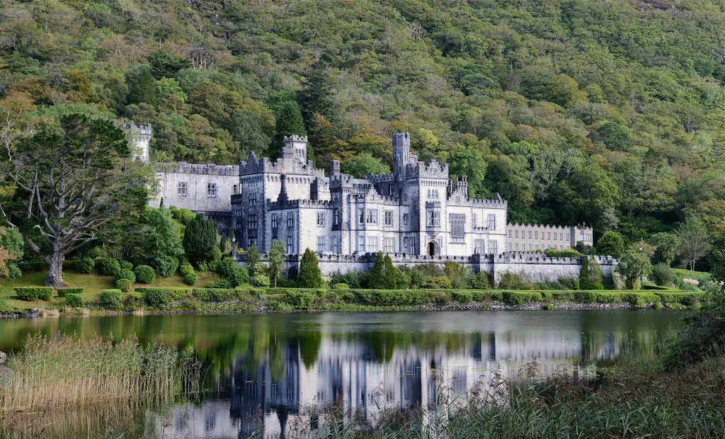 Kylemore Abbey reflected in its lough below the wooded mountain