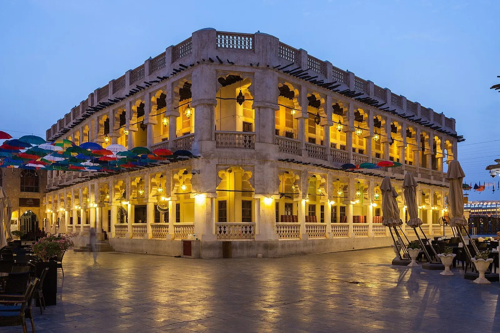 Souq Waqif’s arcades lit at dusk under coloured umbrellas