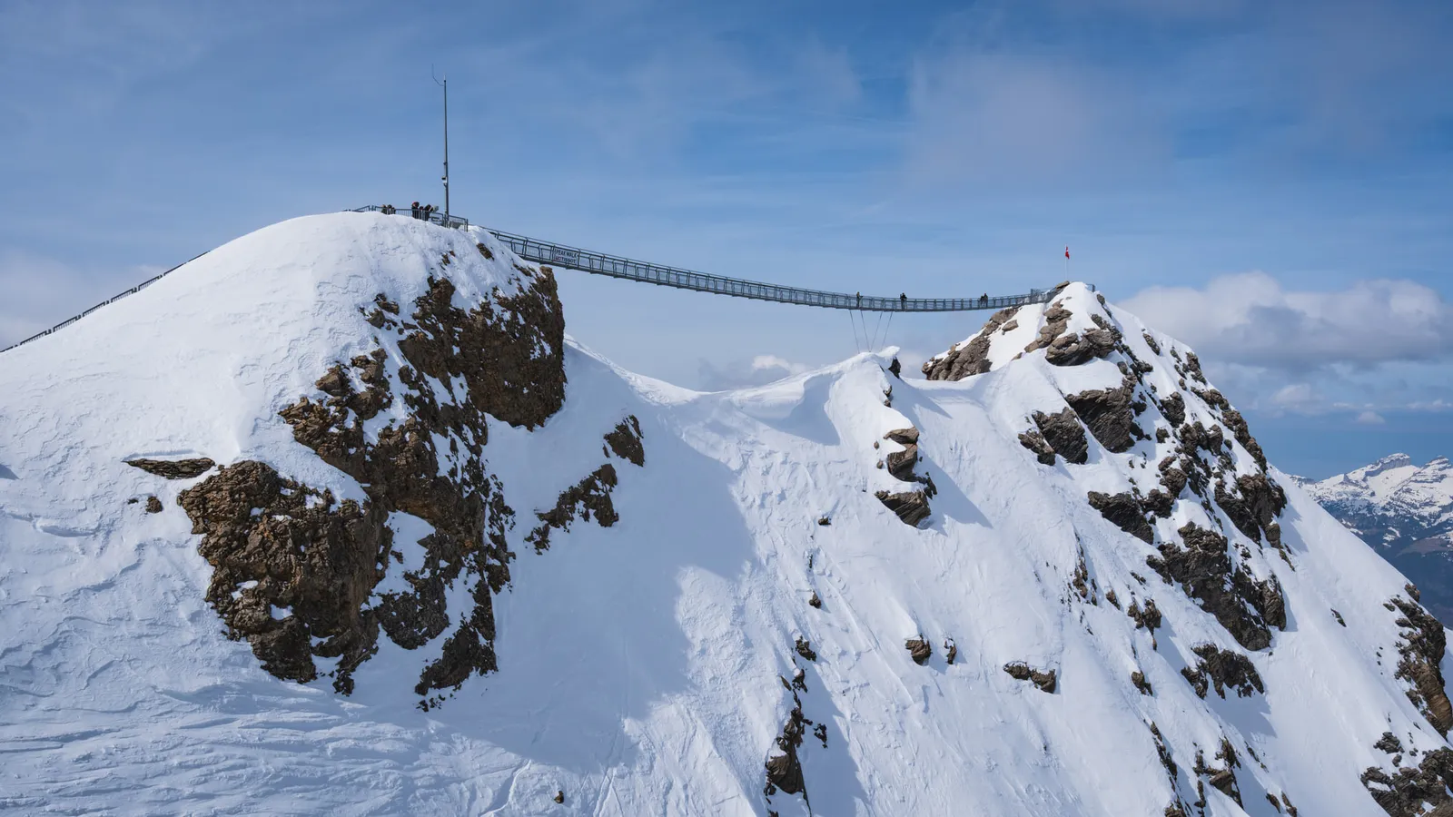 Glacier 3000: a snowy summit and the Peak Walk suspension bridge linking it to the next peak, seen from the roof of the cable car station
