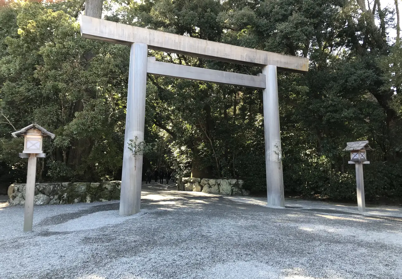 A wooden torii over a gravel path at the outer shrine, 2 sign posts beside it