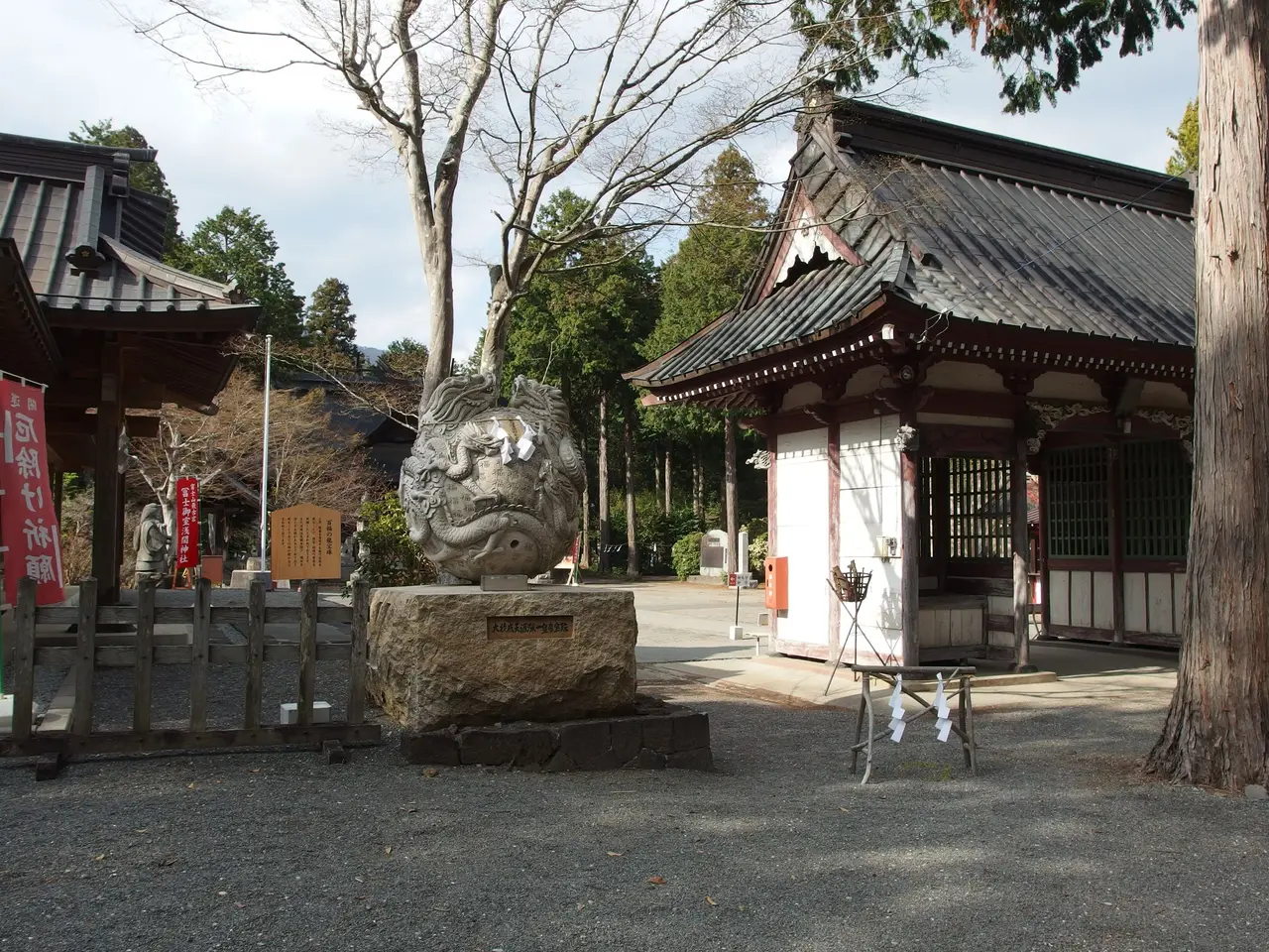 A carved stone and the gate buildings of Fuji Omuro Sengen Shrine among cedars