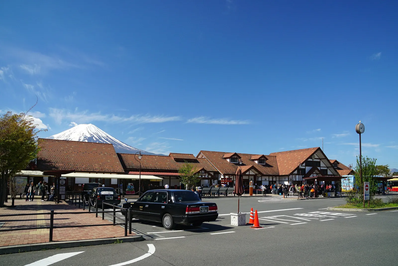Kawaguchiko Station’s timbered building, a taxi waiting and Fuji behind