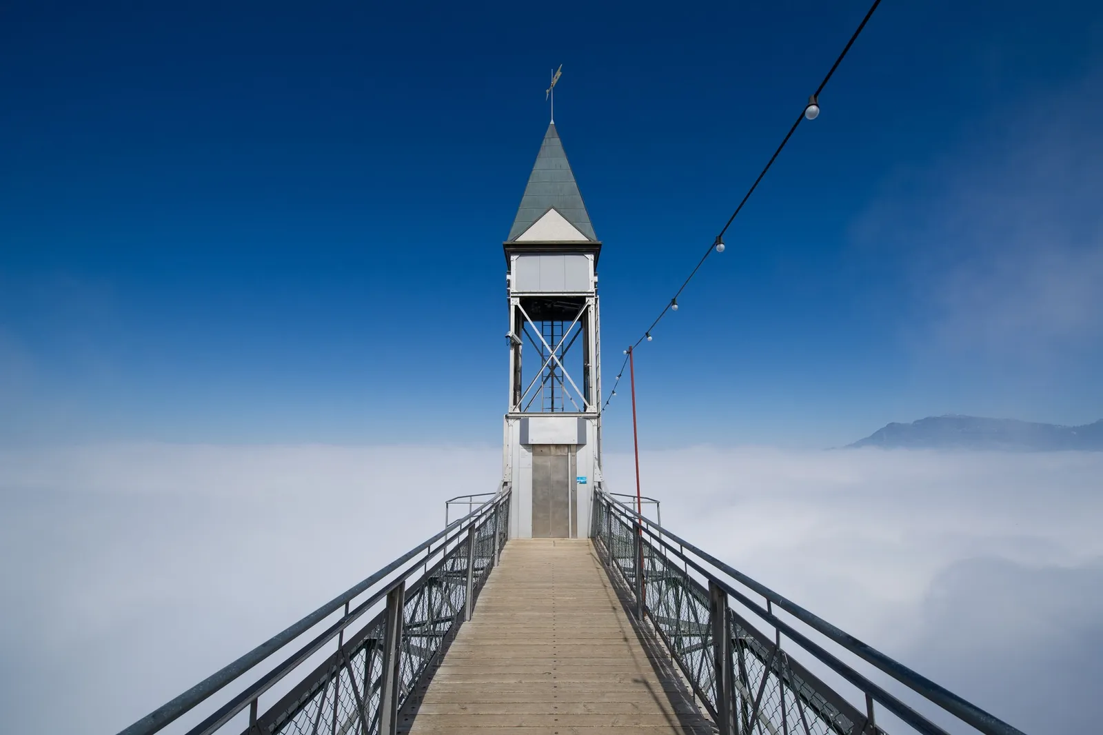 The Hammetschwand Lift: a walkway leading to the lift’s steel tower with its pointed roof, above a sea of cloud
