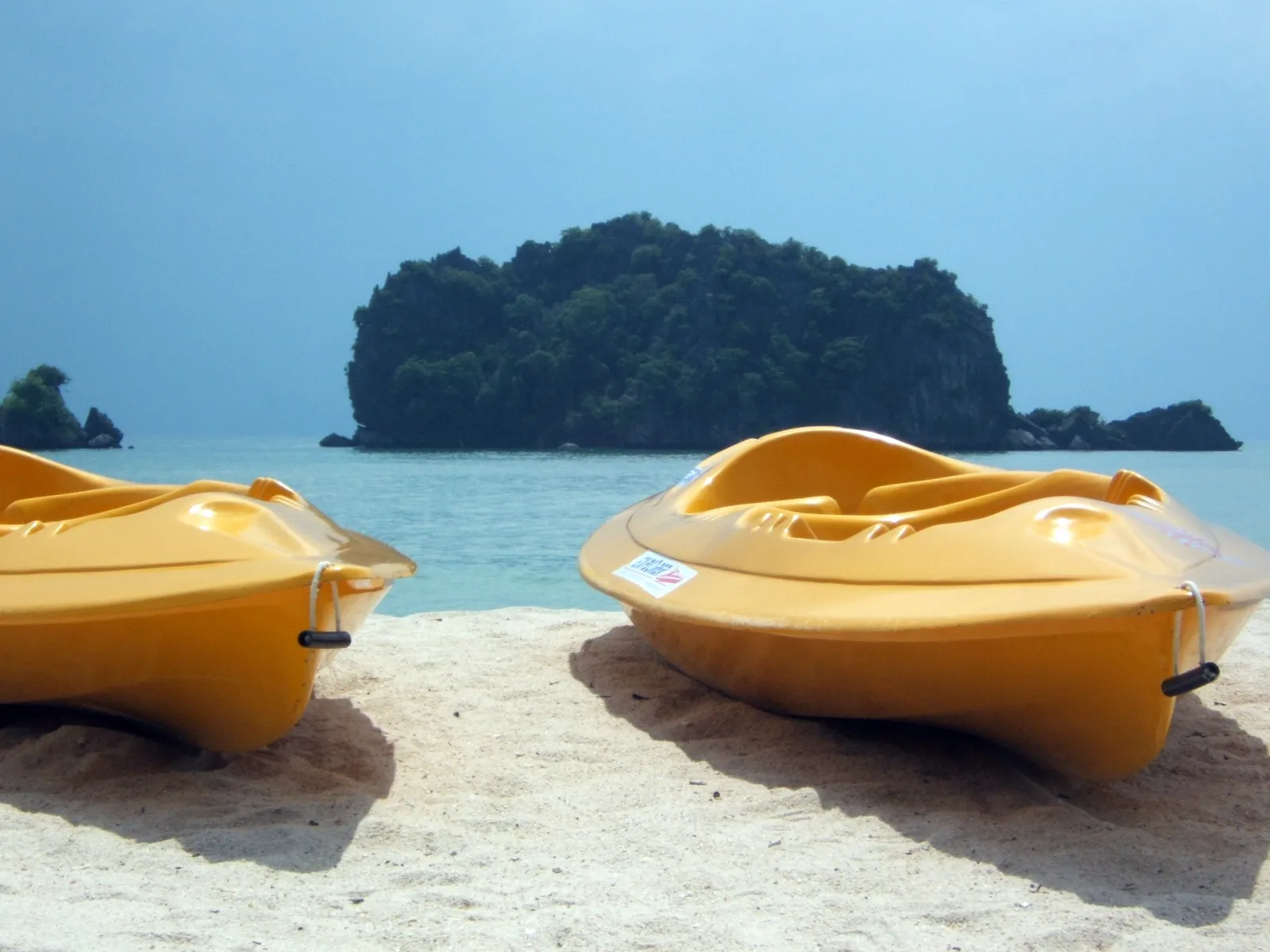 2 yellow kayaks on the sand at Tanjung Rhu, a wooded islet offshore
