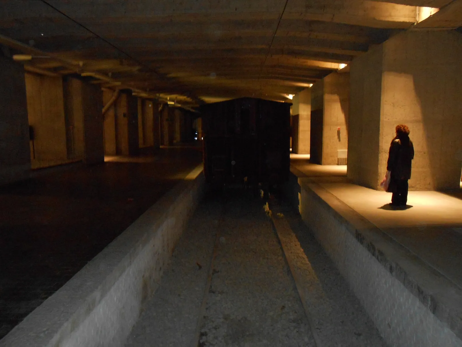 The original platform beneath Milano Centrale, now the Shoah Memorial, with a goods wagon and a visitor