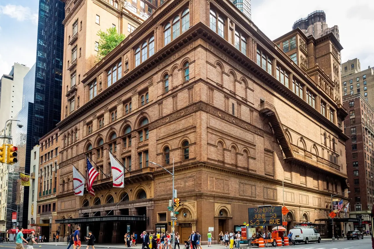 Carnegie Hall on the corner of 57th Street, its brick façade and the flags over the entrance