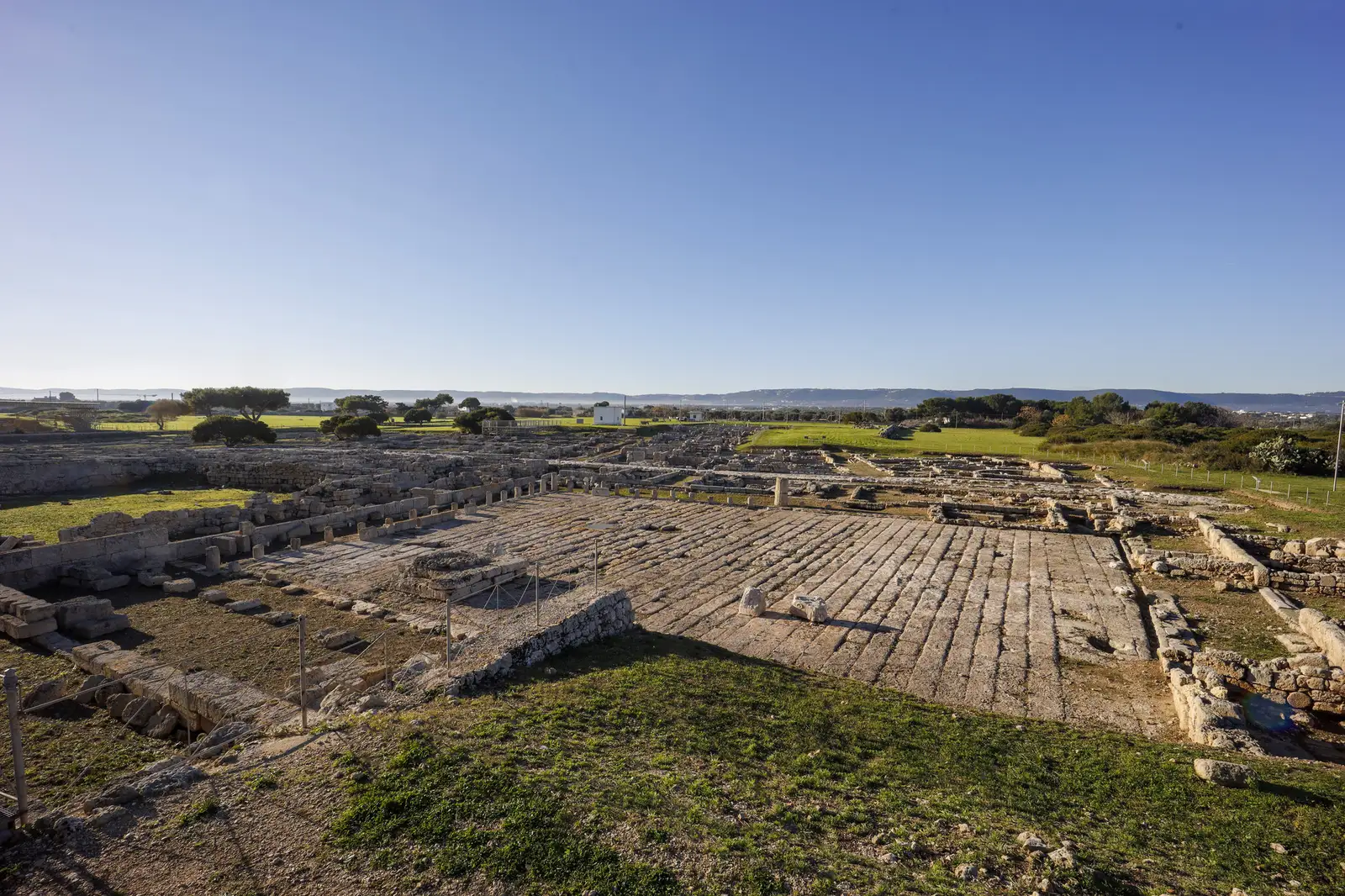 The excavations of ancient Egnazia: the paved market square with the remains of its portico and hills on the horizon.