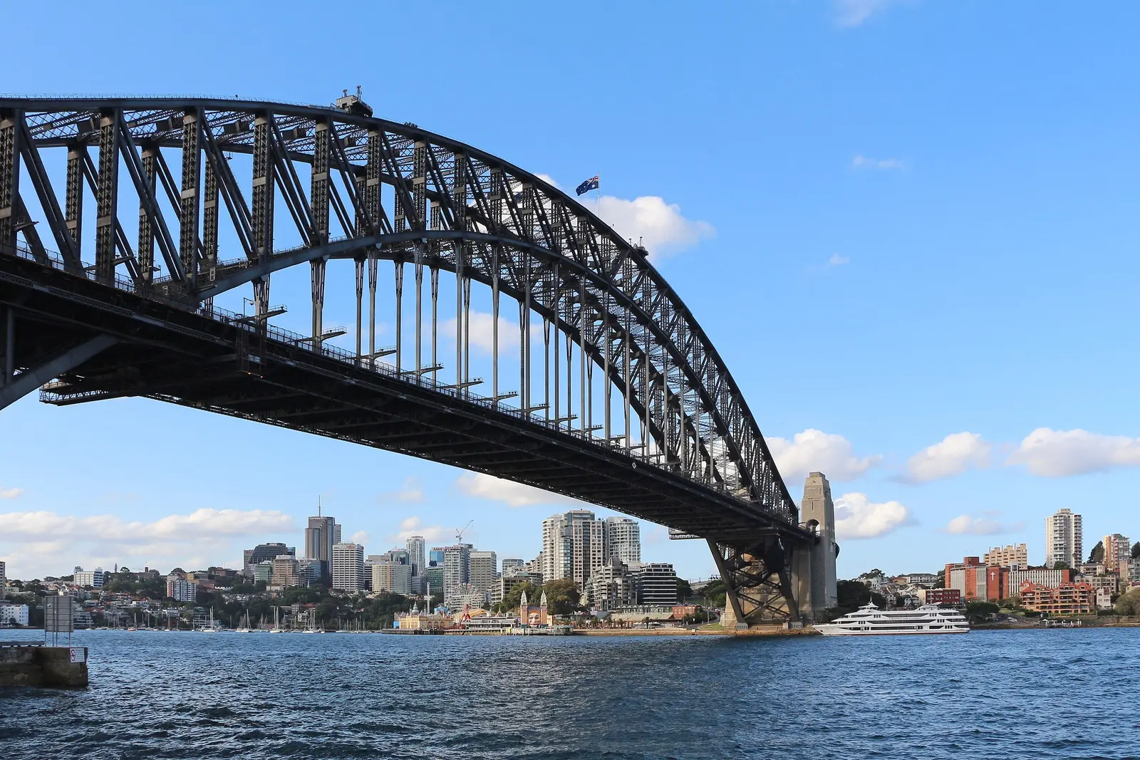 The steel arch of the Sydney Harbour Bridge over the water, a pylon at its end