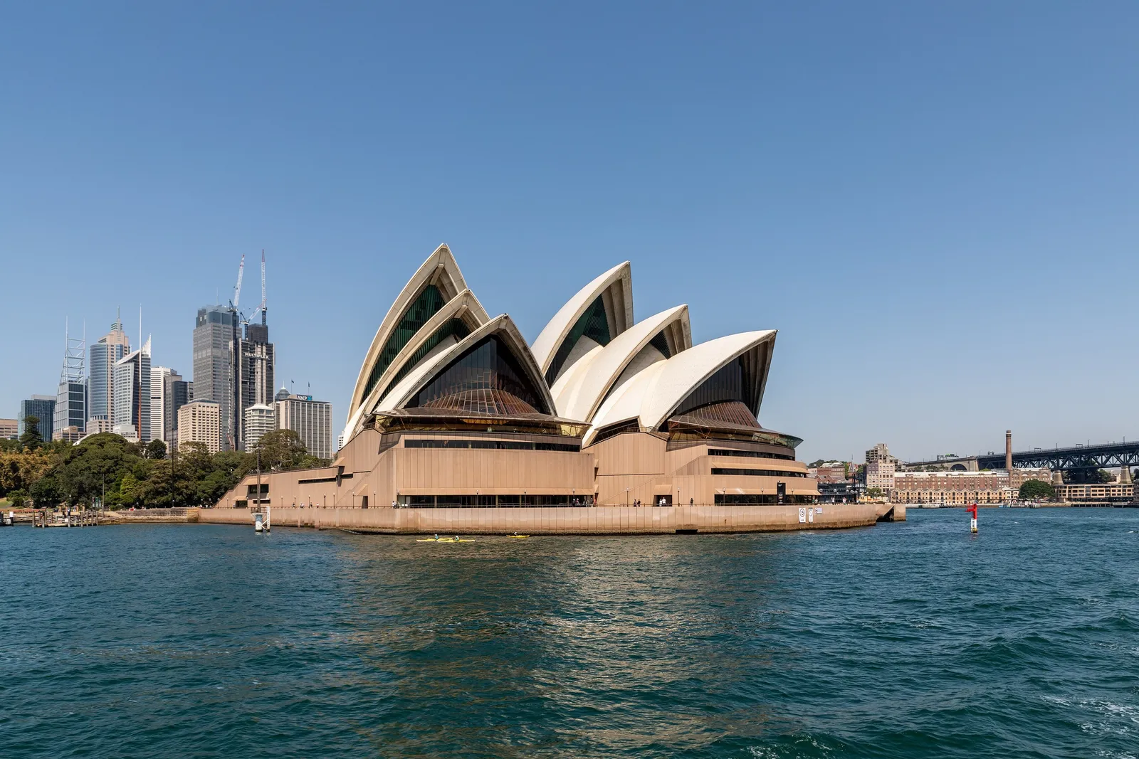 The white sails of the Sydney Opera House seen from the water, the city skyline behind