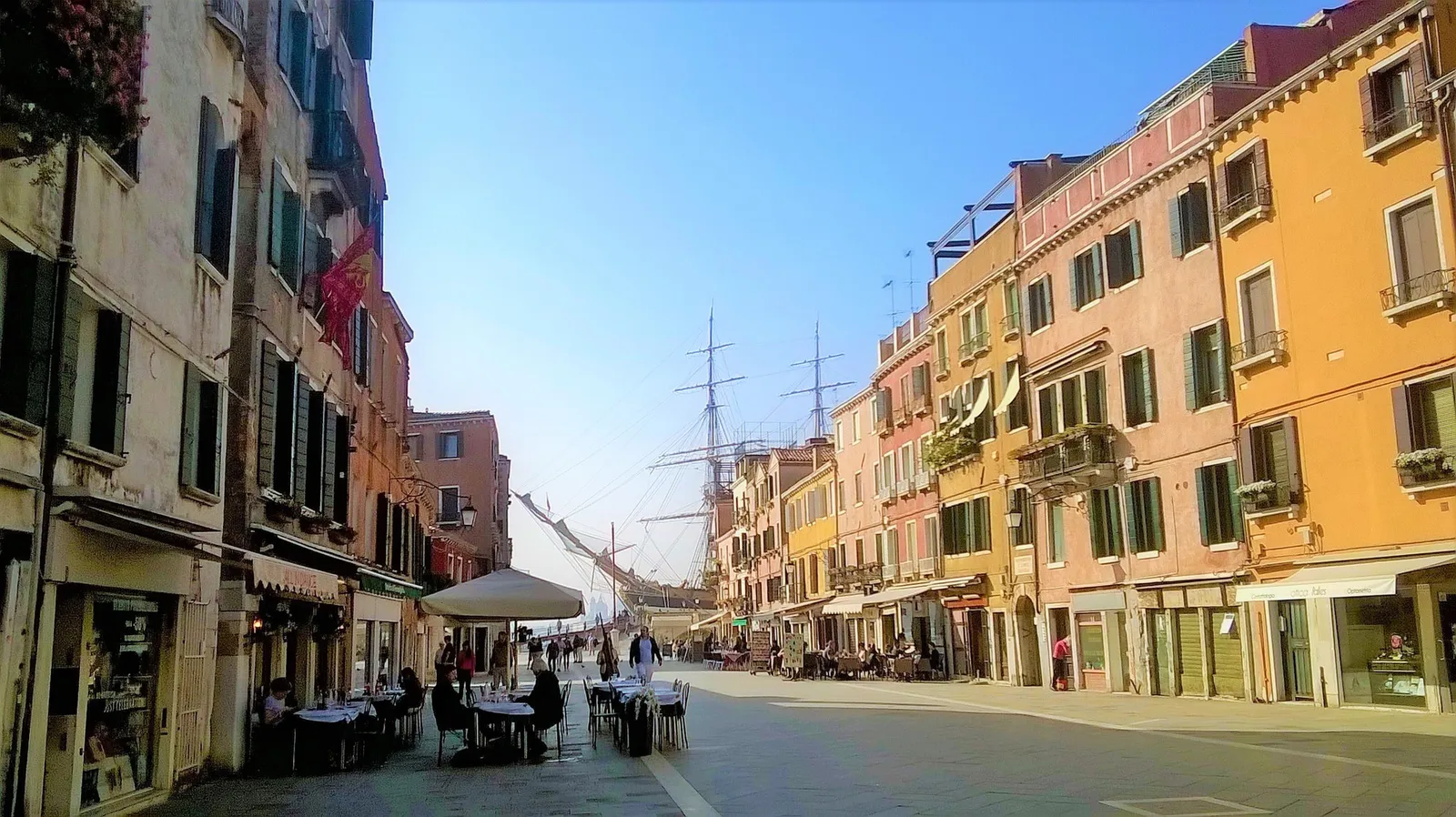 Via Garibaldi in Castello, with cafe tables and the masts of a sailing ship at the far end