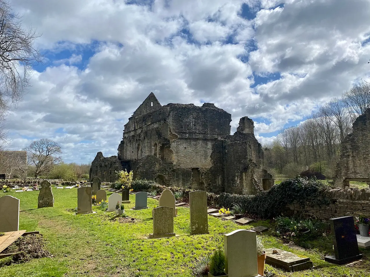 The ruins of Minster Lovell Hall beyond the churchyard
