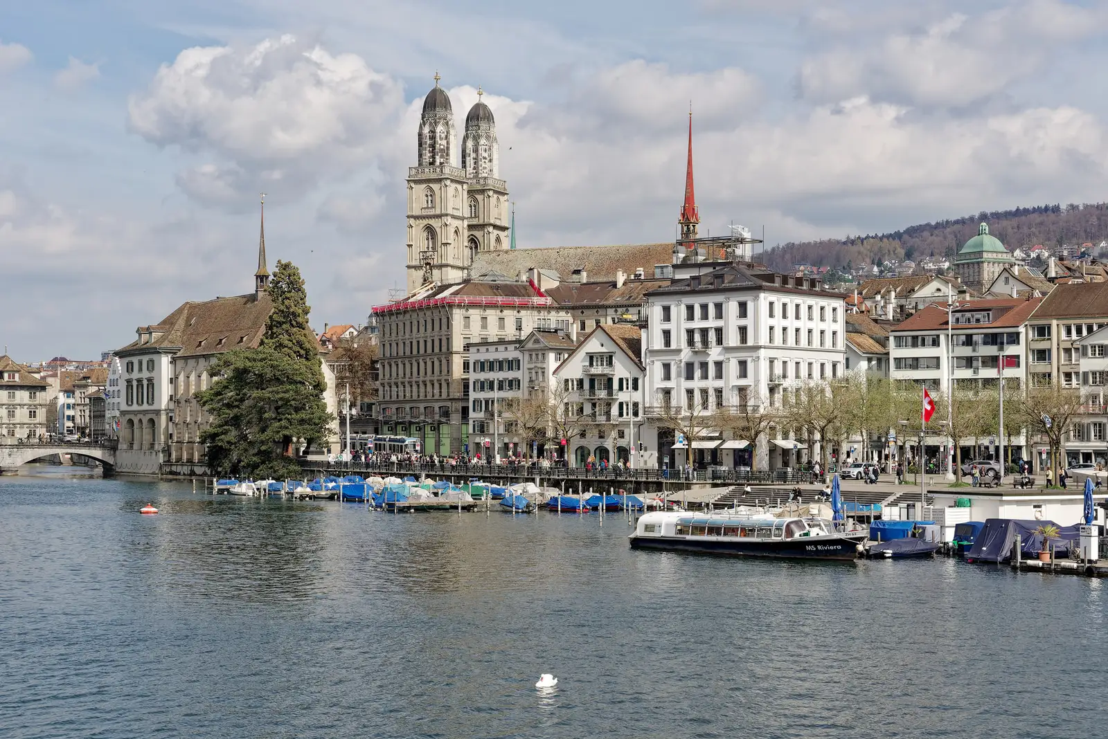 The twin towers of the Grossmünster above the Limmat and the old town, with boats on the river