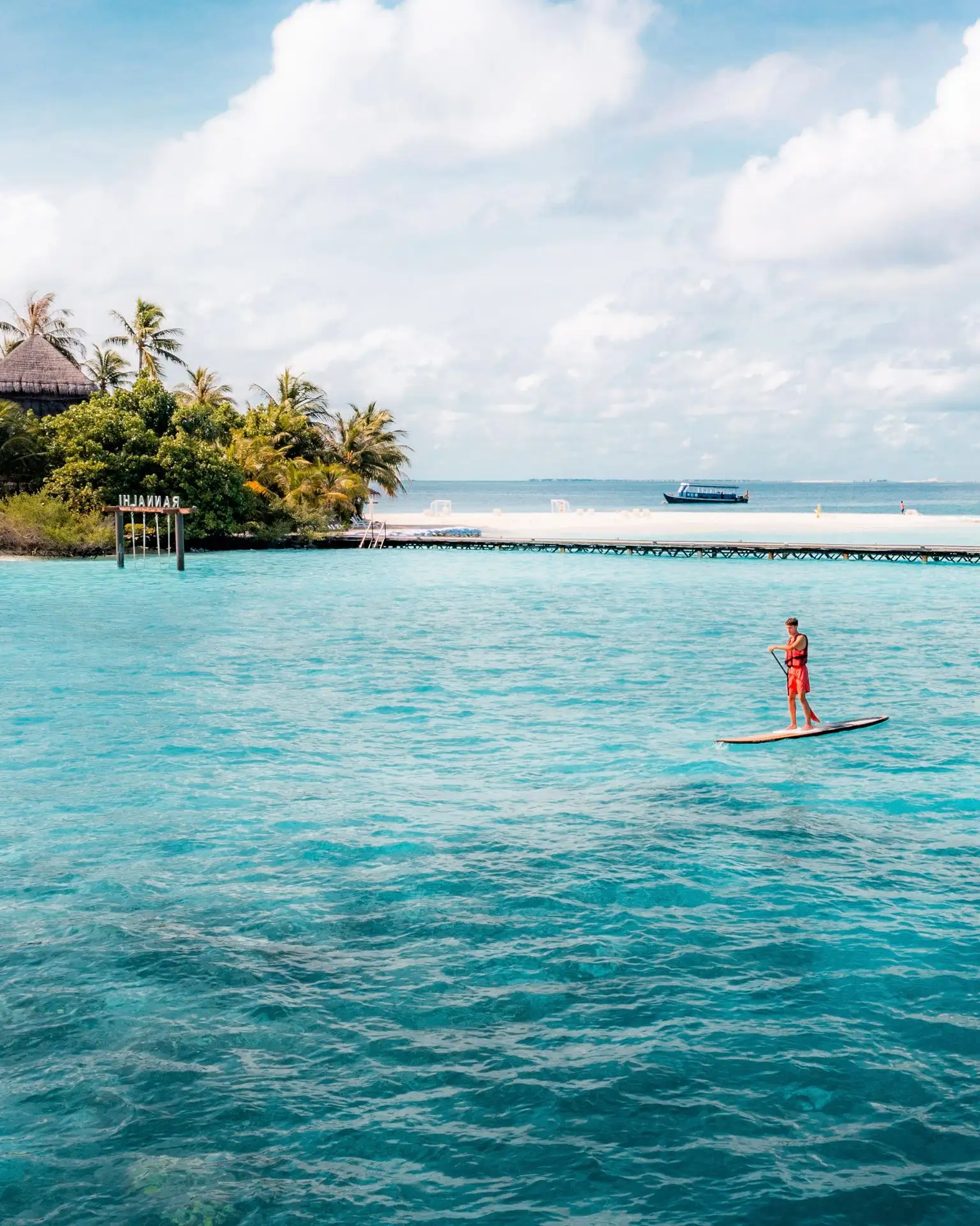 A paddleboarder standing on the lagoon, the island behind