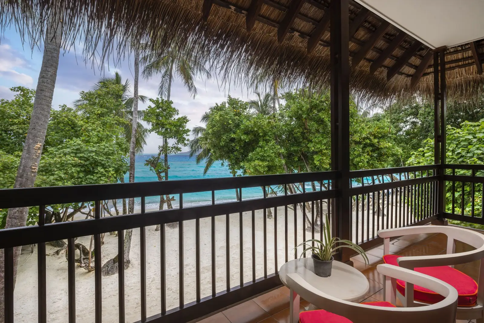 A Classic Ocean View balcony: 2 chairs, the railing and the sea between the palms