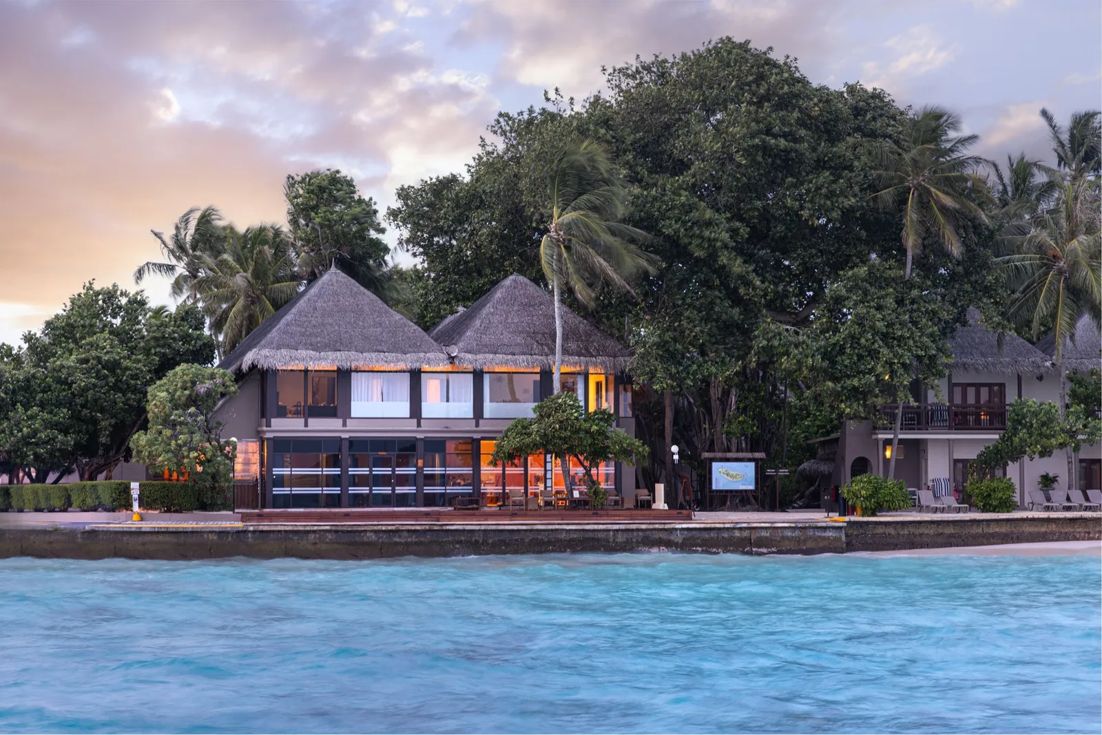 The spa’s 2-storey pavilion at the water’s edge at dusk, its windows lit