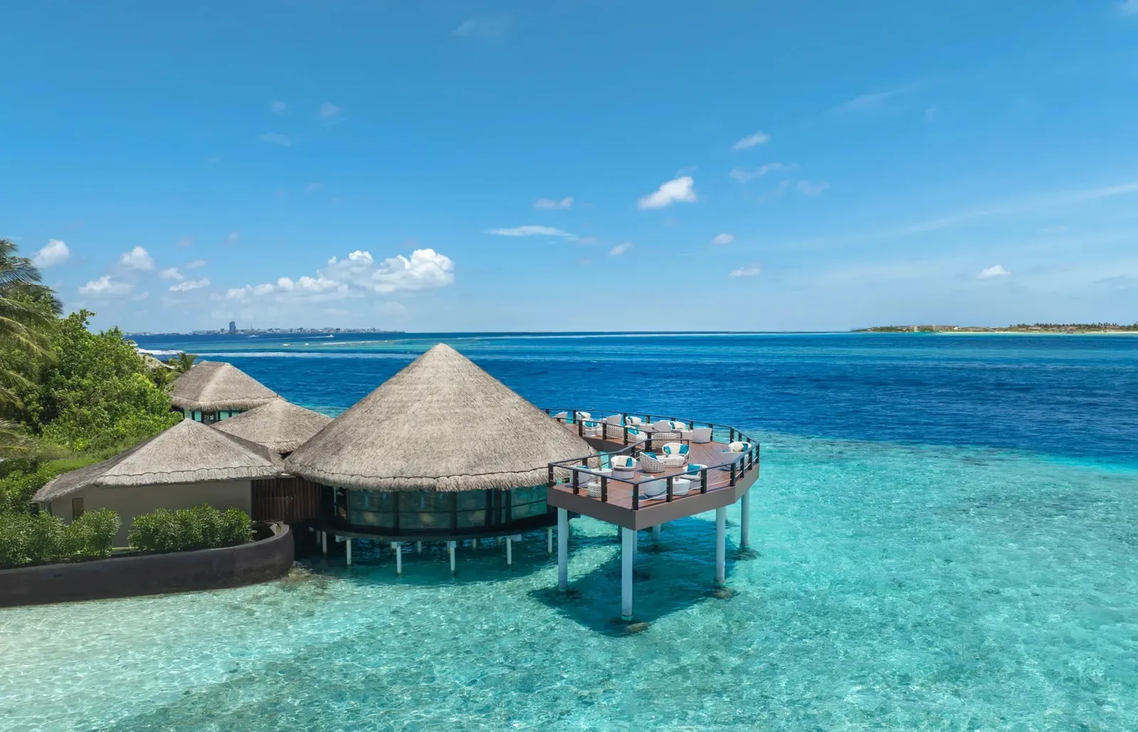 The Kandholi Bar over the water, its deck above the lagoon and a city on the horizon