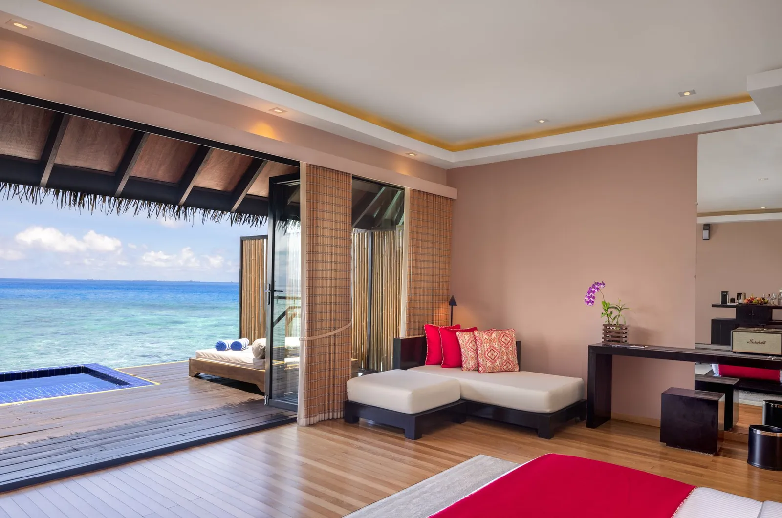 A Sunset Water Villa bedroom, the red throw and the pool on the deck.