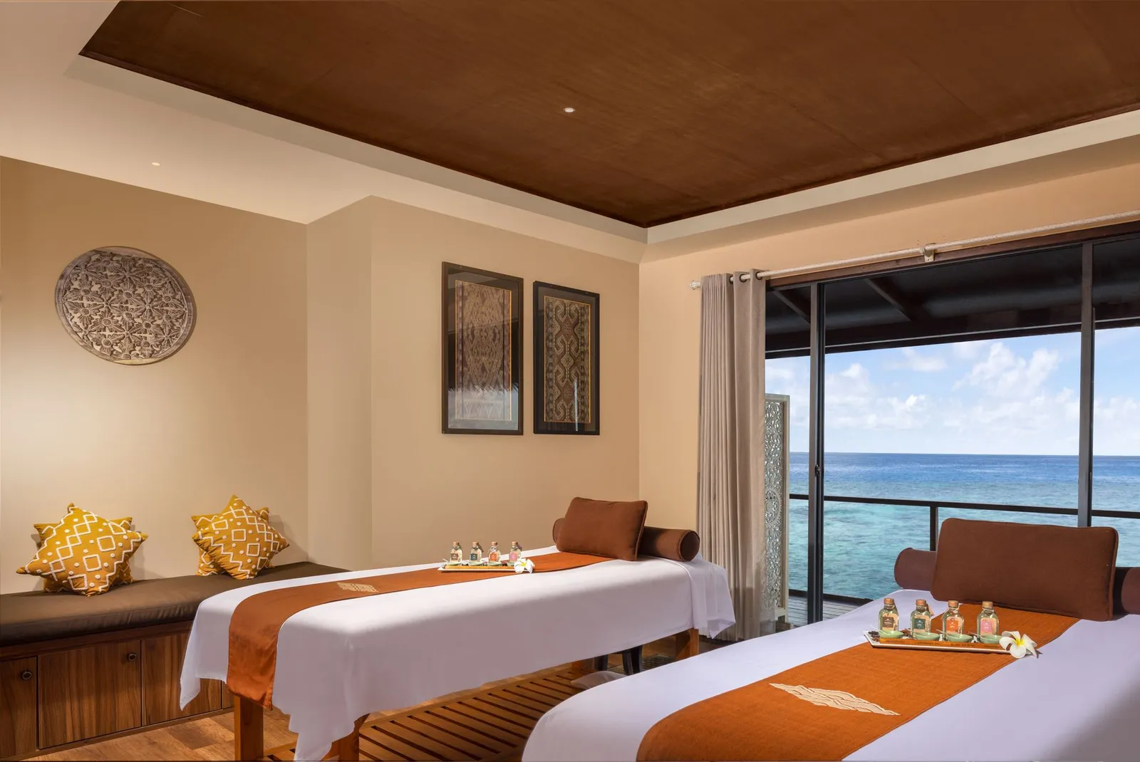 A spa room with 2 massage beds and a window on the sea