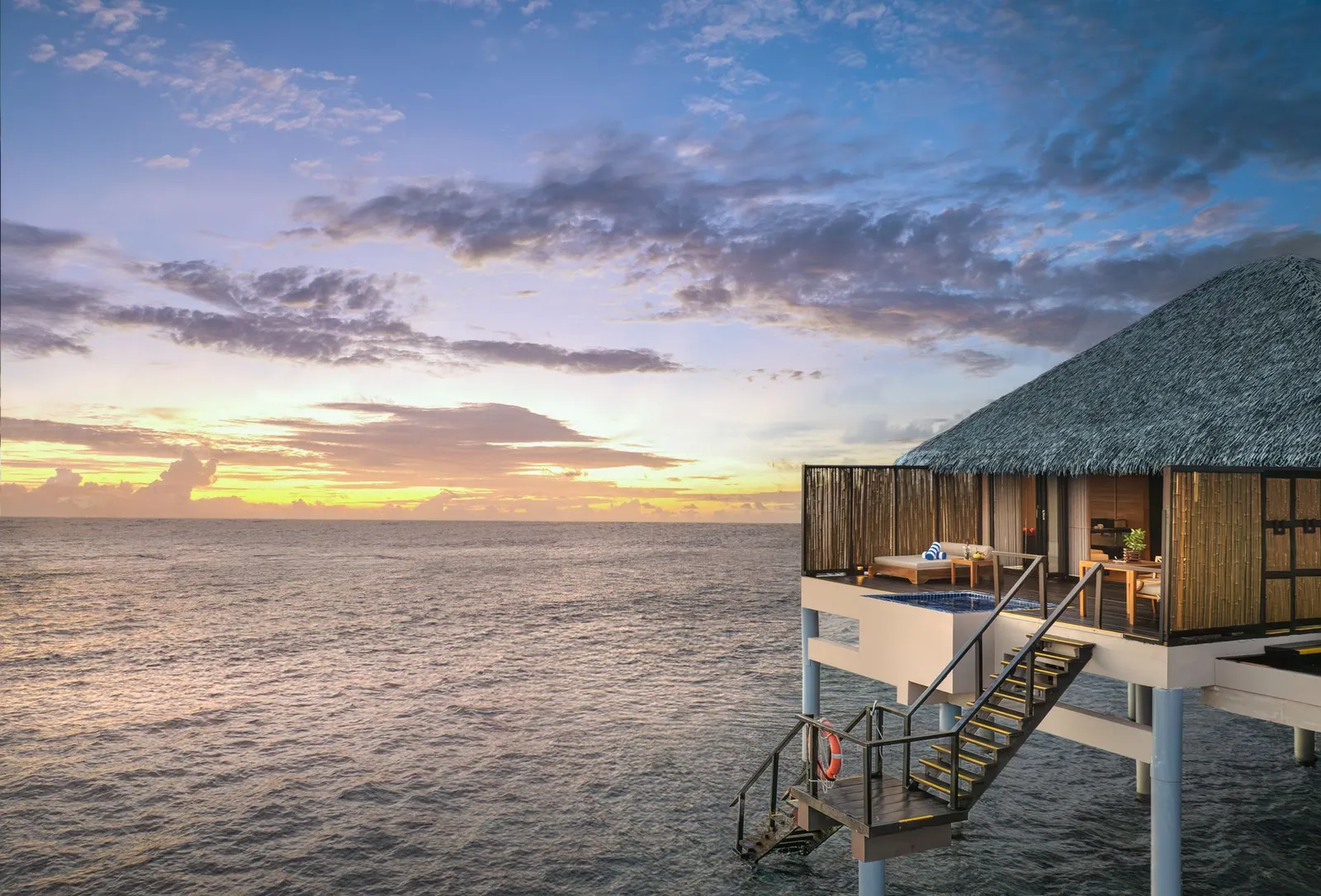 A Sunset Water Villa at dusk, its ladder down into the sea