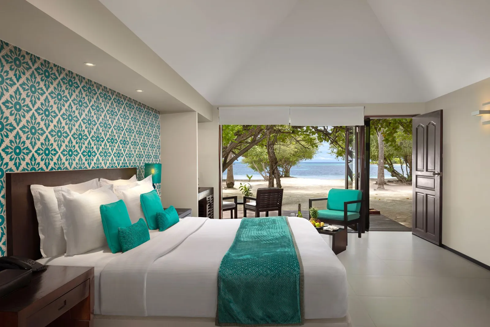 A Beach Villa: the bed with turquoise cushions and the door open to the beach