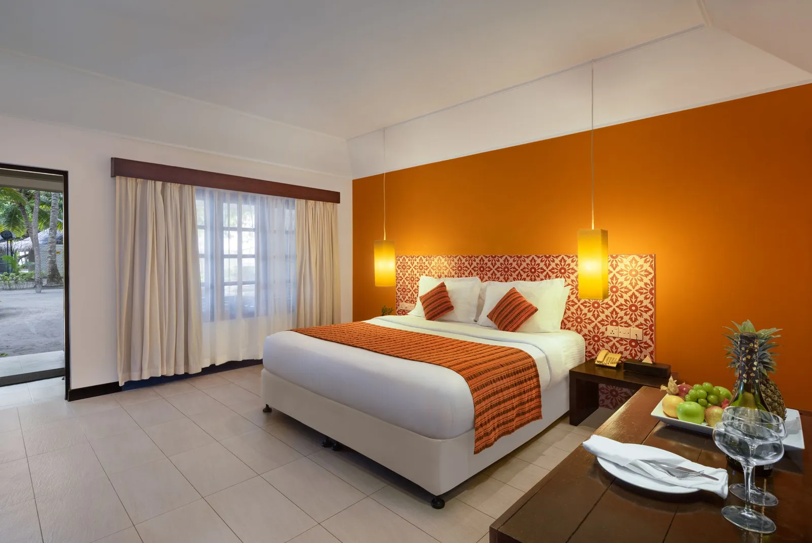 A Garden Villa bedroom, the bed against an orange wall