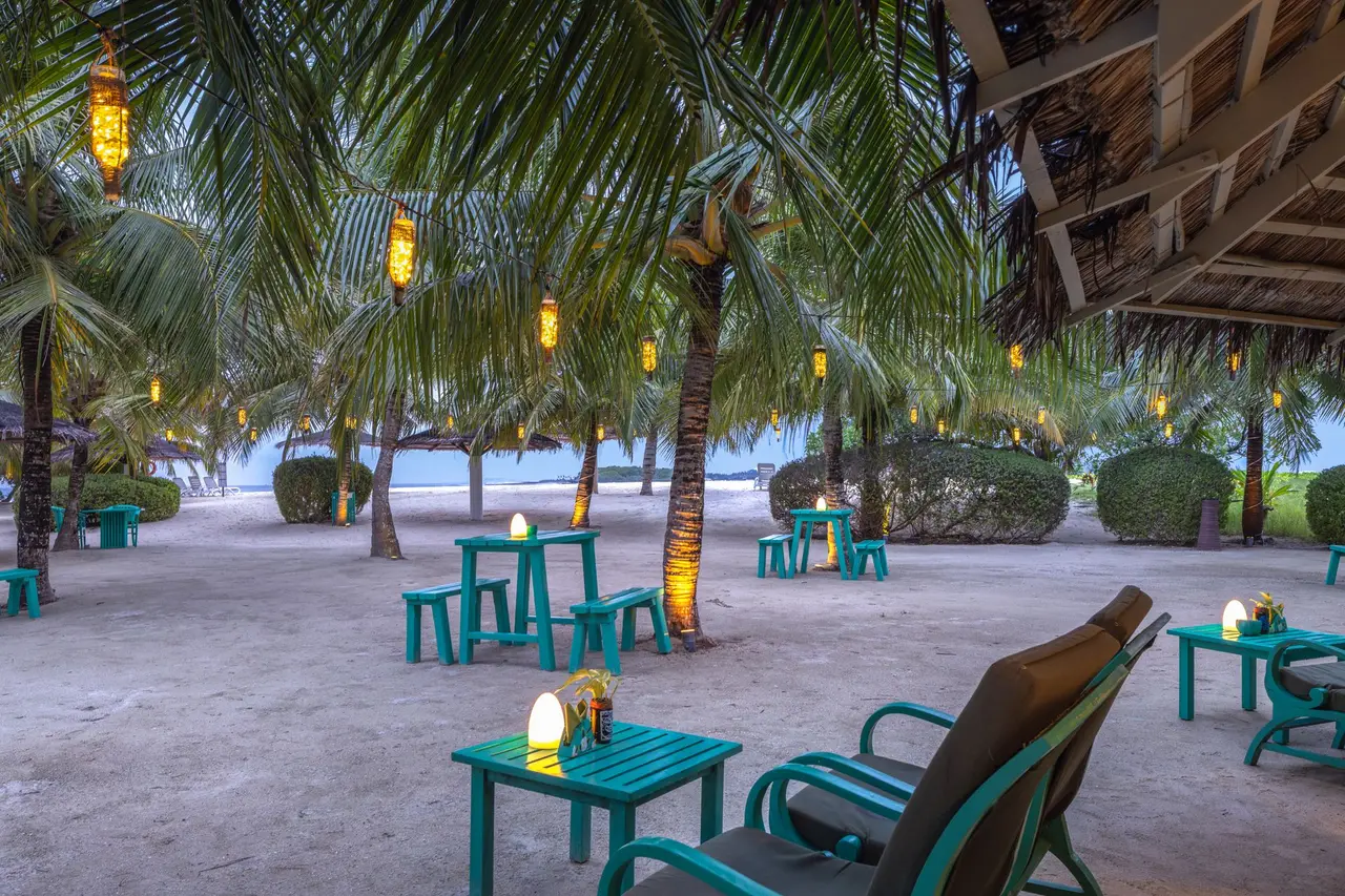 The Tiki Bar in the evening, lanterns in the palms and turquoise chairs on the sand