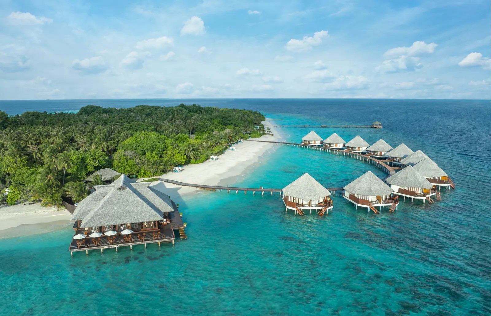 The water villas and their restaurant from the air, the beach and palms behind