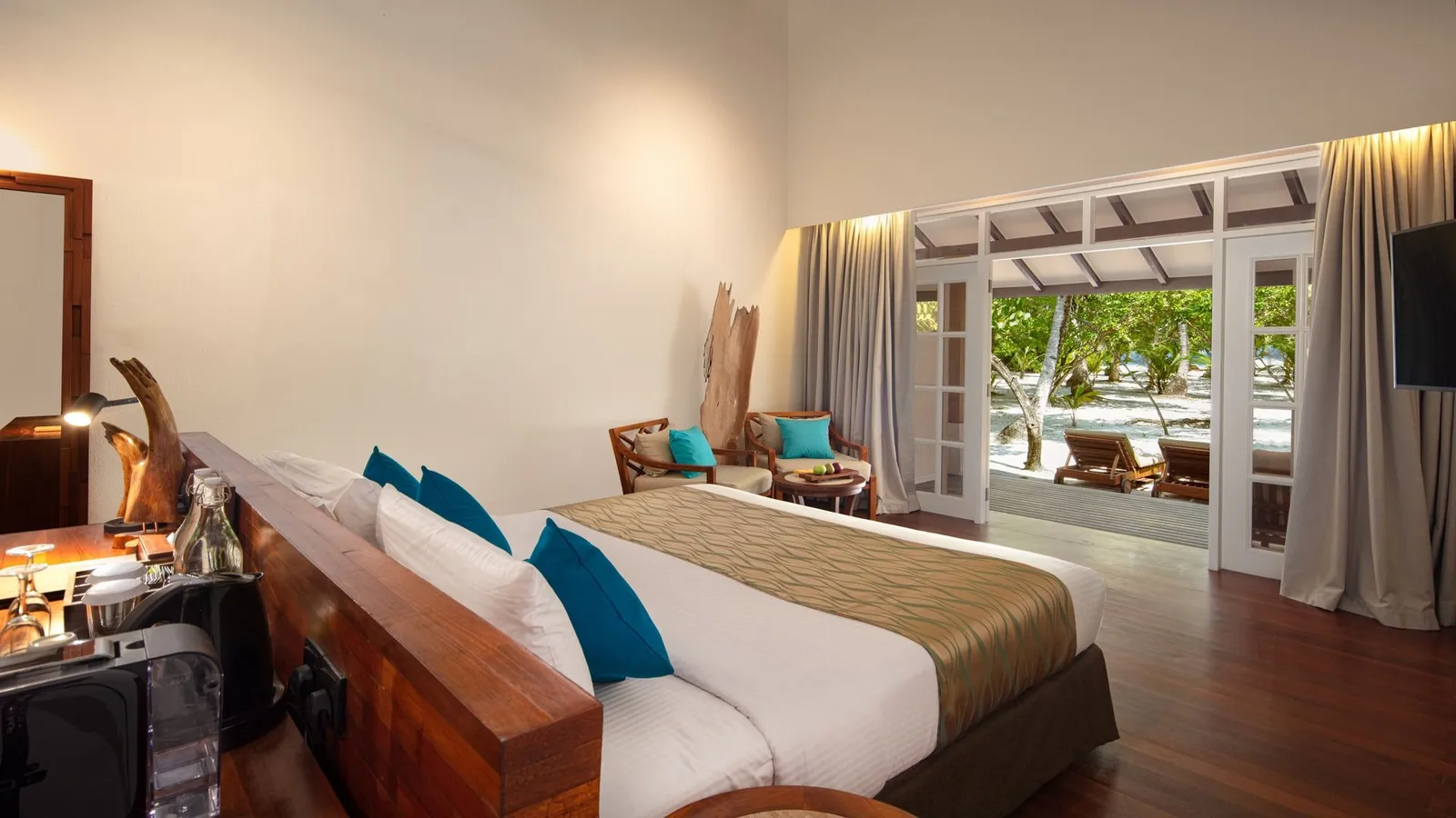 A Deluxe Beach Villa: the bed with blue cushions and doors open towards the beach