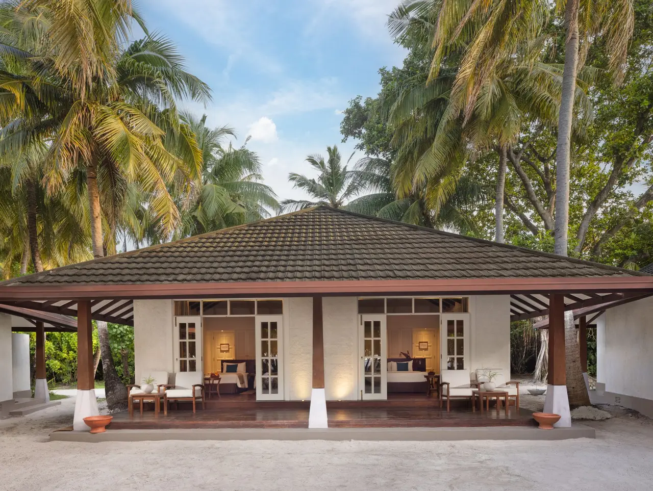 A family villa among the palms, with its veranda and turquoise loungers on the sand