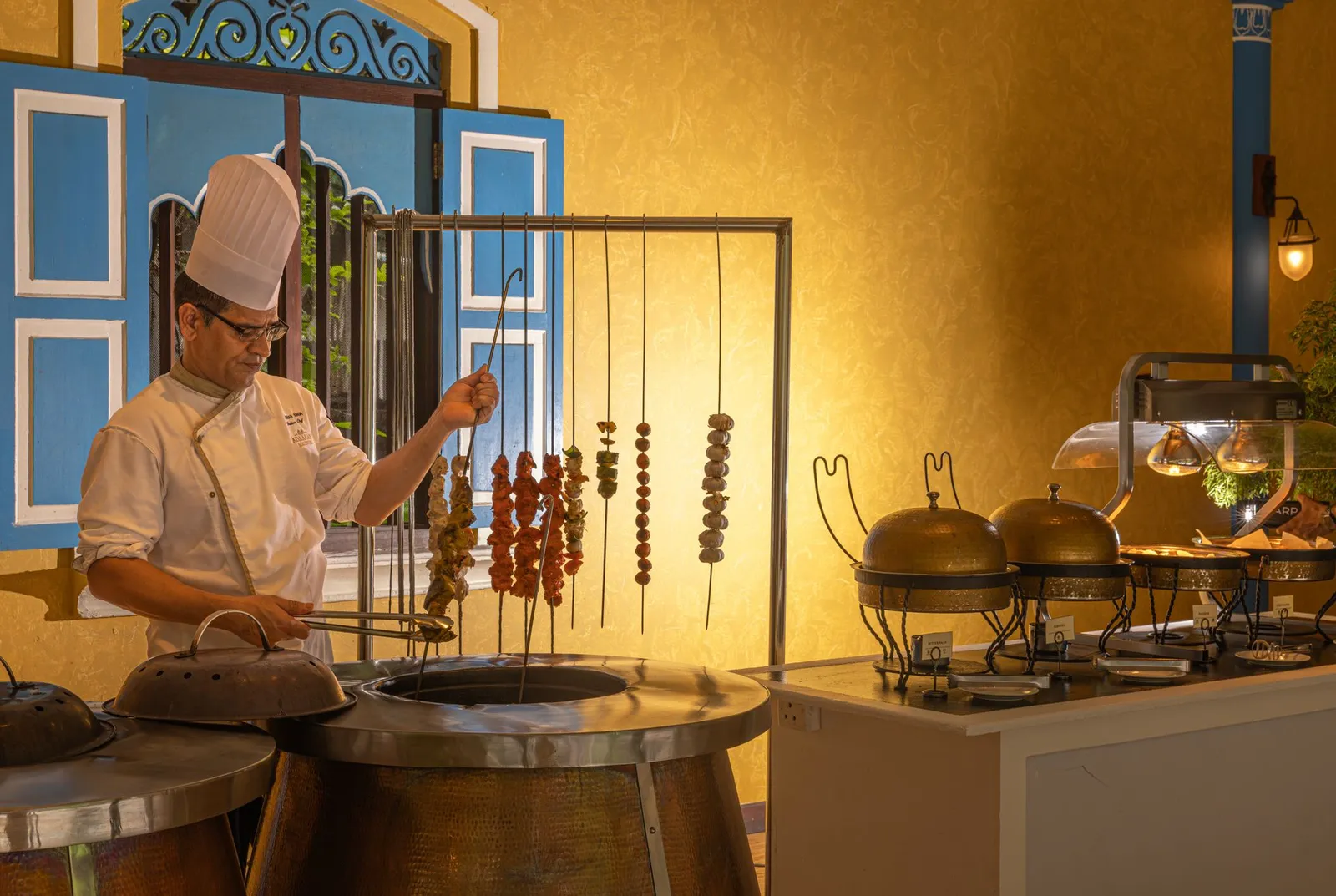 At the Sufura a cook prepares skewers at the tandoor