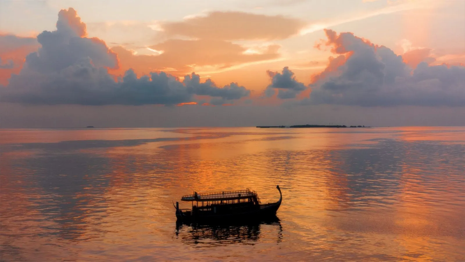 A dhoni in the lagoon at sunset, an orange sky over the water