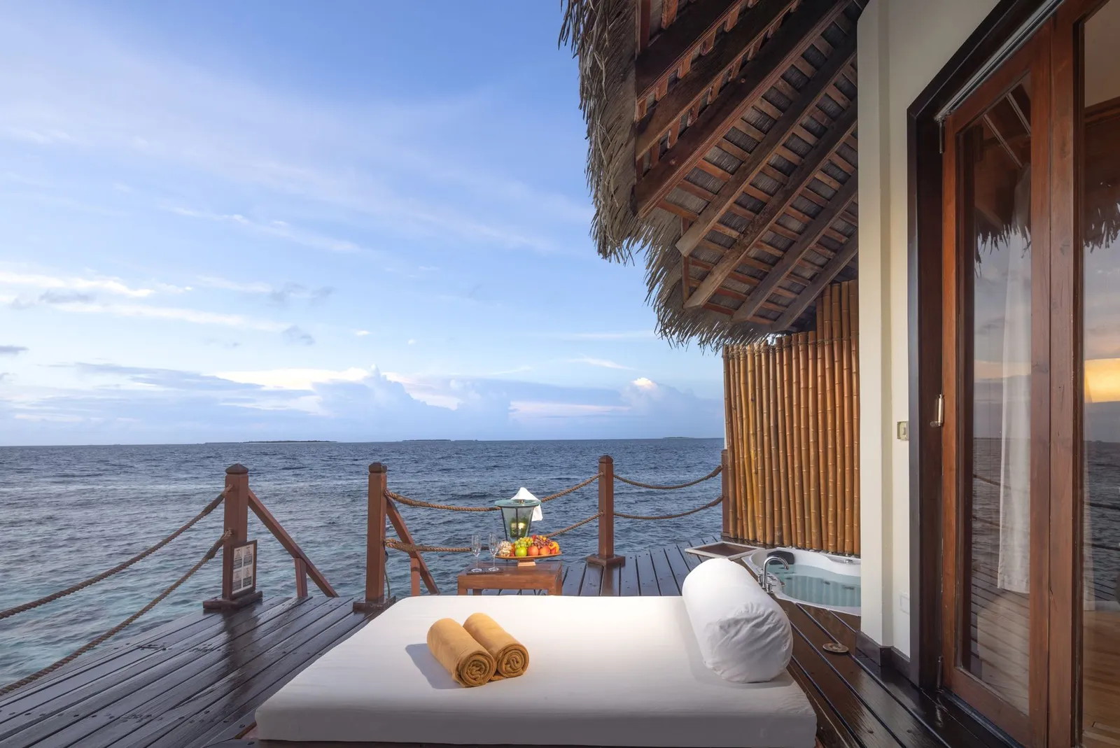 A water-villa deck: the daybed, rolled towels and the ocean