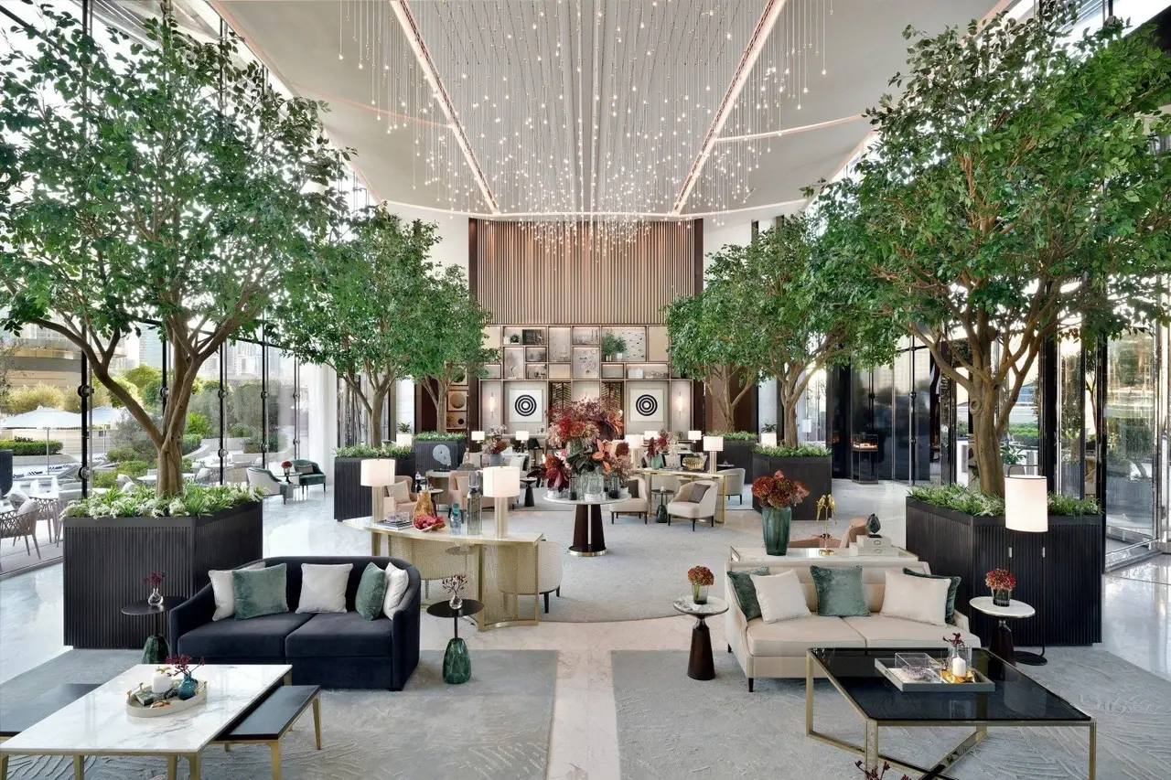 The lobby under a ceiling of lights, with trees and sofas