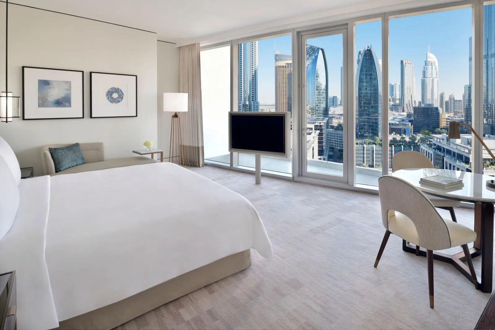 A room with a king bed, a desk and the city through the glass