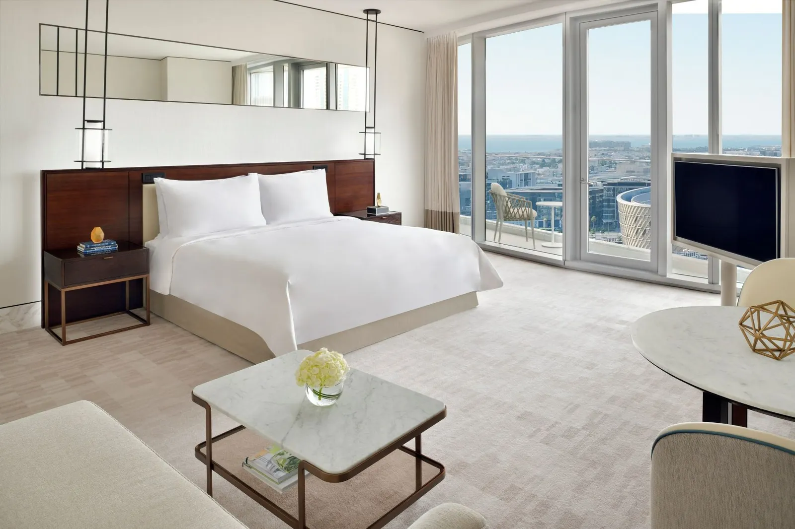 The Junior Suite with its bed, a marble table and the city through the windows