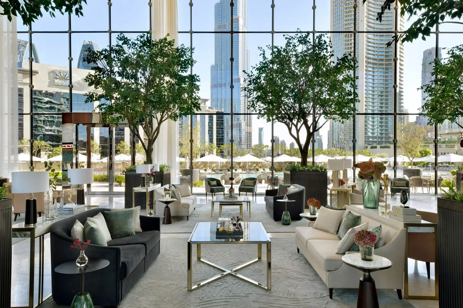 The lobby lounge among trees, with the Burj Khalifa beyond the glass