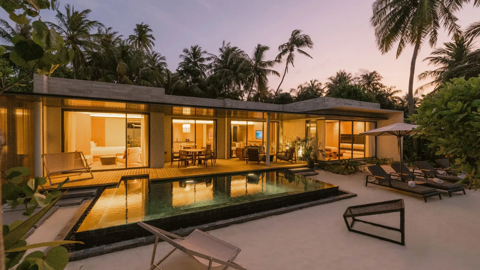 The 2-bedroom villa facade and pool at dusk.
