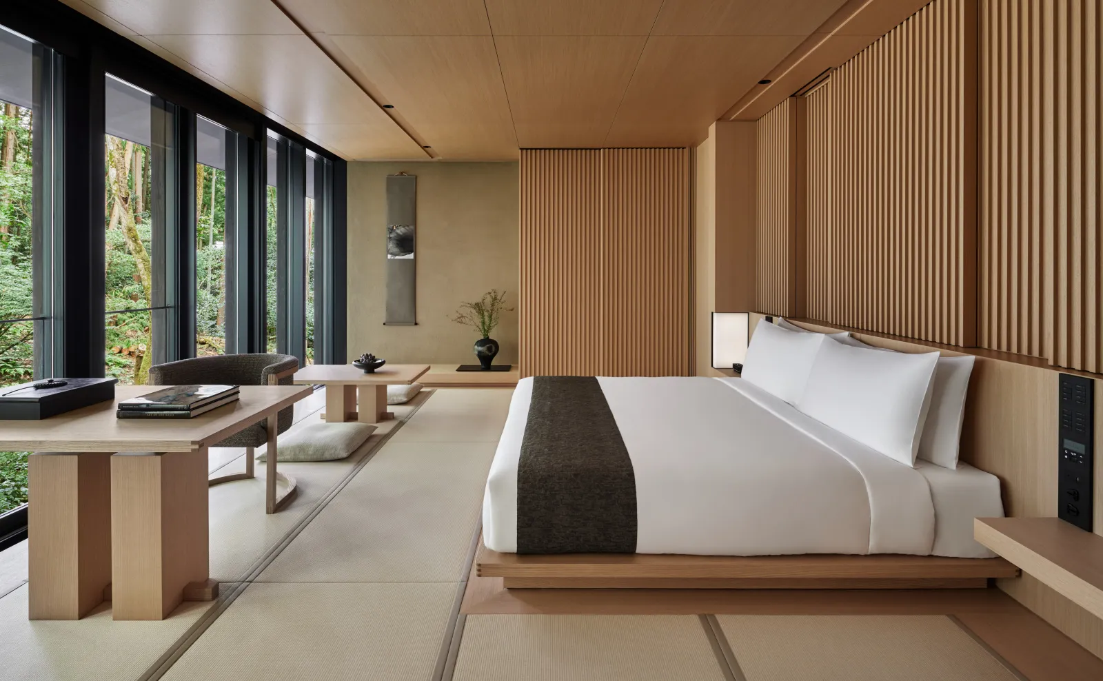 A Susuki room: the king bed on tatami, the wooden desk and a wall of glass onto the green.