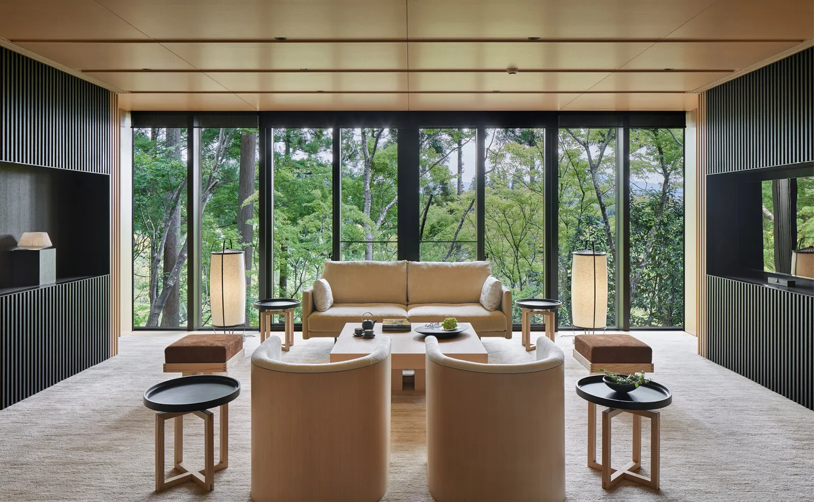 The Takagamine Pavilion’s living room: pale sofas and armchairs in front of a tall window onto the forest.