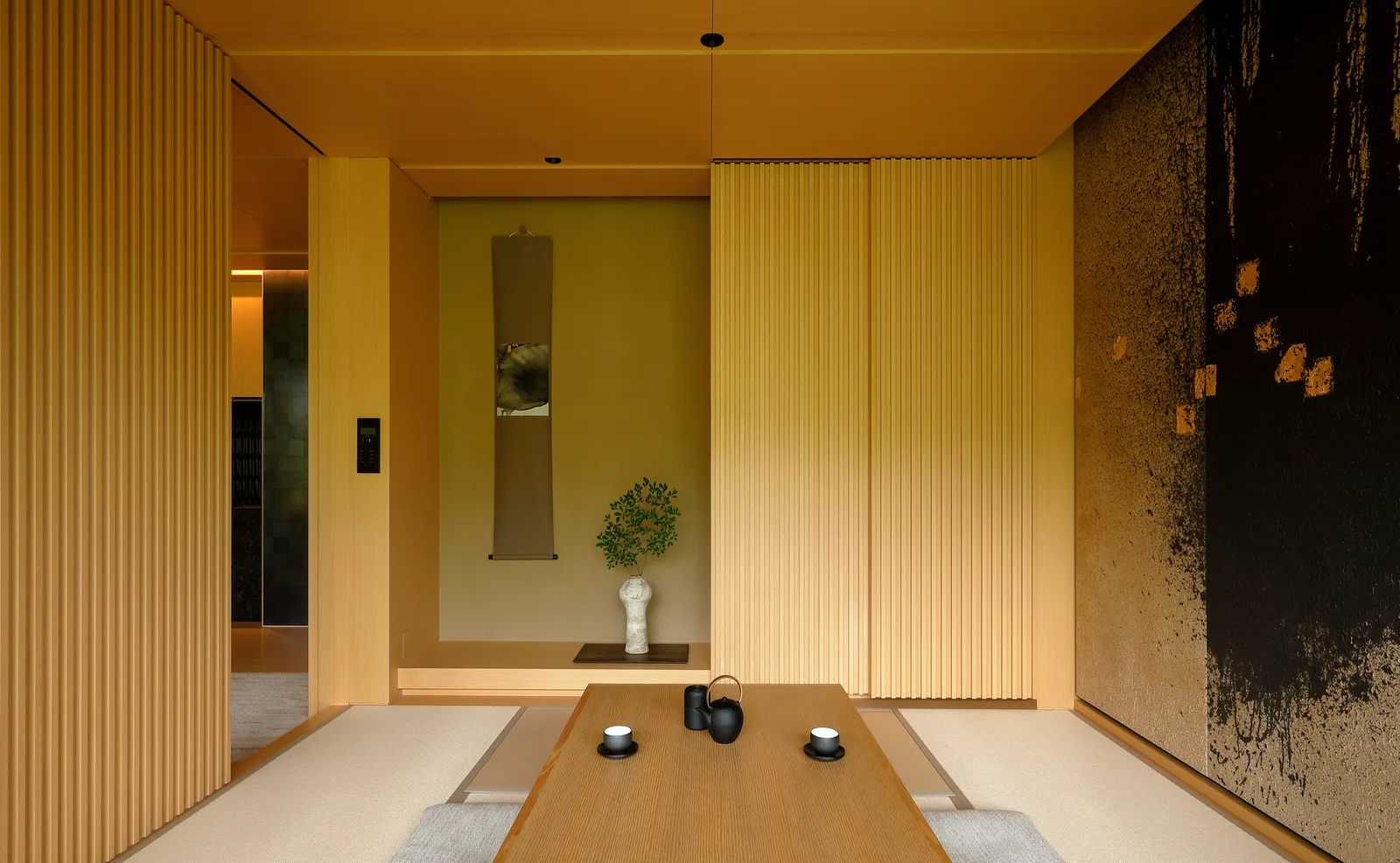 The Takagamine Suite’s tatami room, with the low table, a tea set, the tokonoma and a dark painted panel.