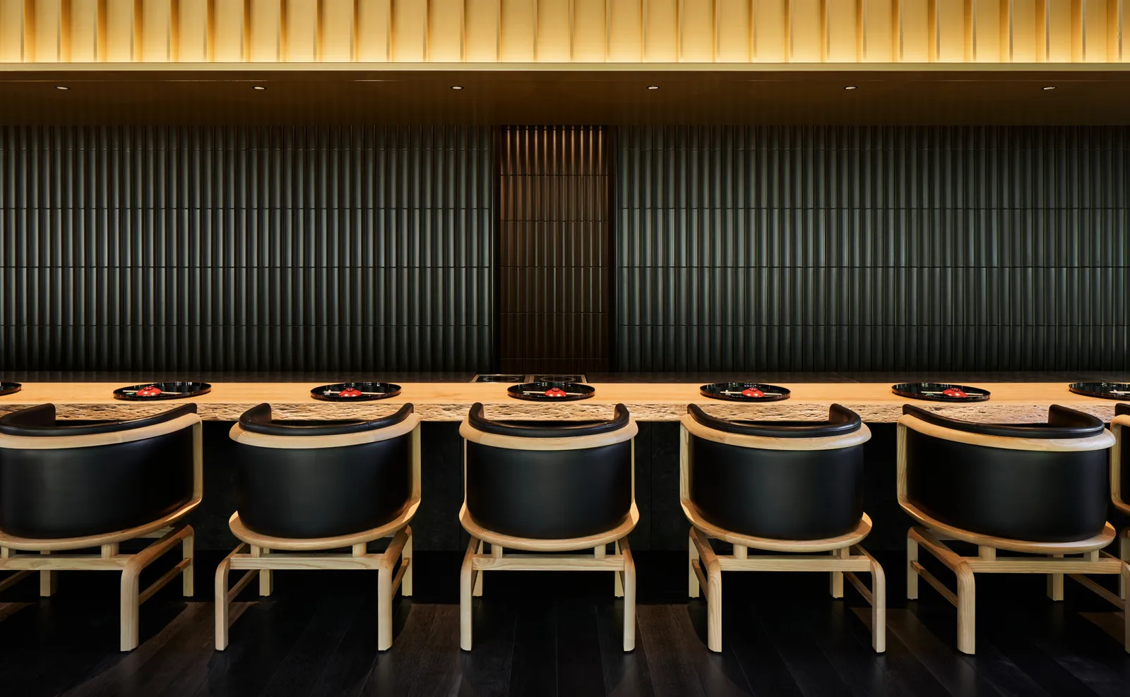 Taka-An’s pale timber counter, with its black chairs and the dark slatted wall under the golden ceiling.