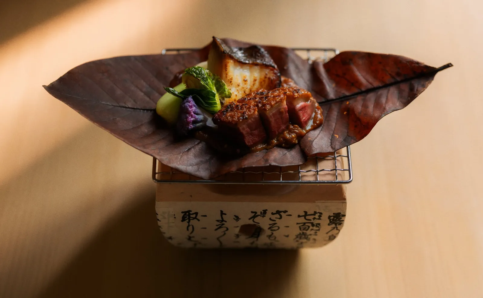 A dish at Akari: fish and vegetables on a leaf, over a small grill