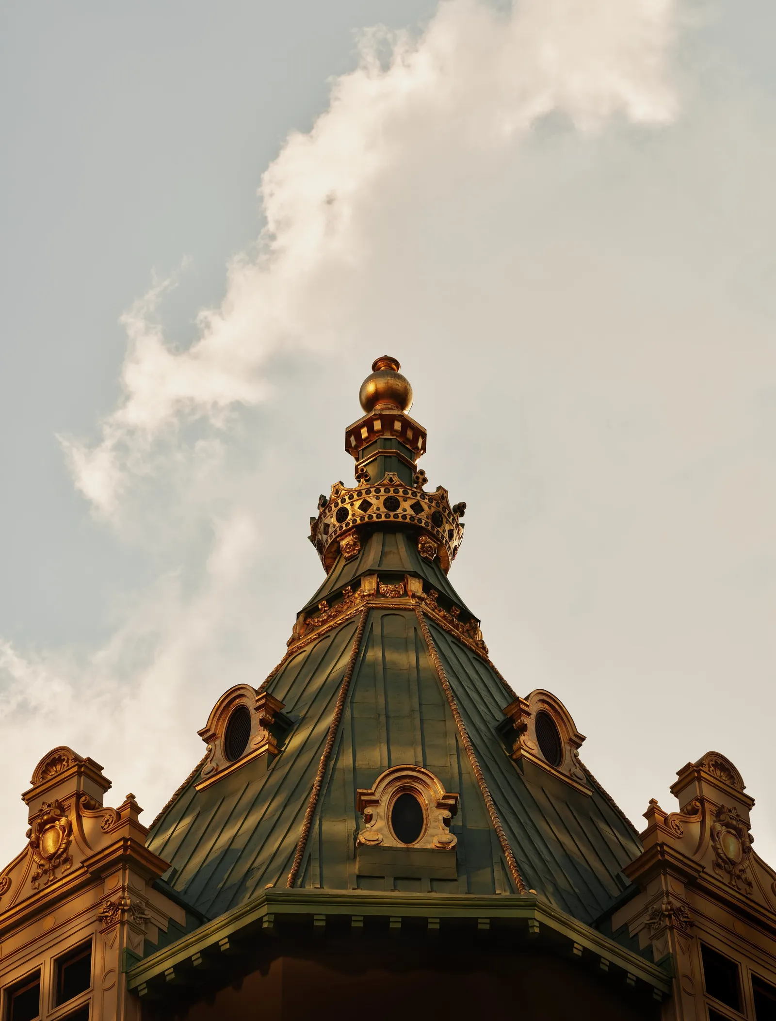The Crown Building’s gilded dome among pinnacles and carvings, against a cloudy sky