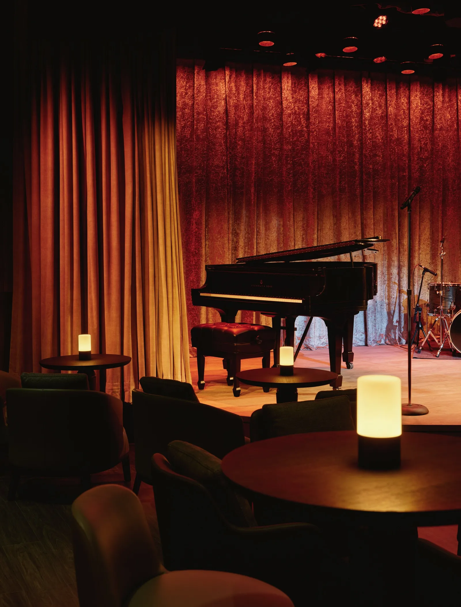 The Jazz Club stage: a grand piano between red velvet curtains, candlelit tables