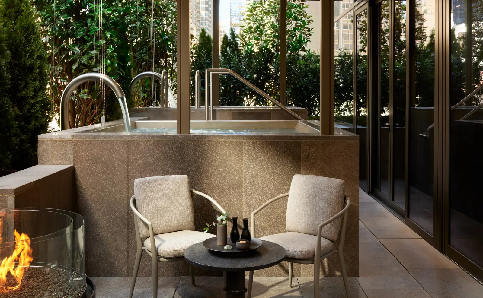 A Spa House terrace: a stone tub, 2 armchairs and plants all round