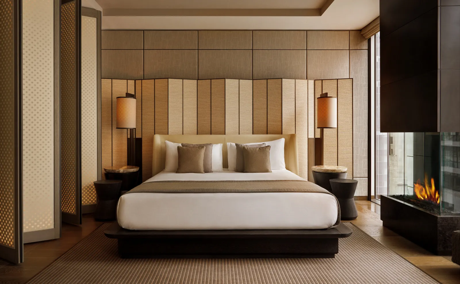 Deluxe suite bedroom with neutral tones, upholstered wall panels, and soft lighting at Aman New York on 56th Street.