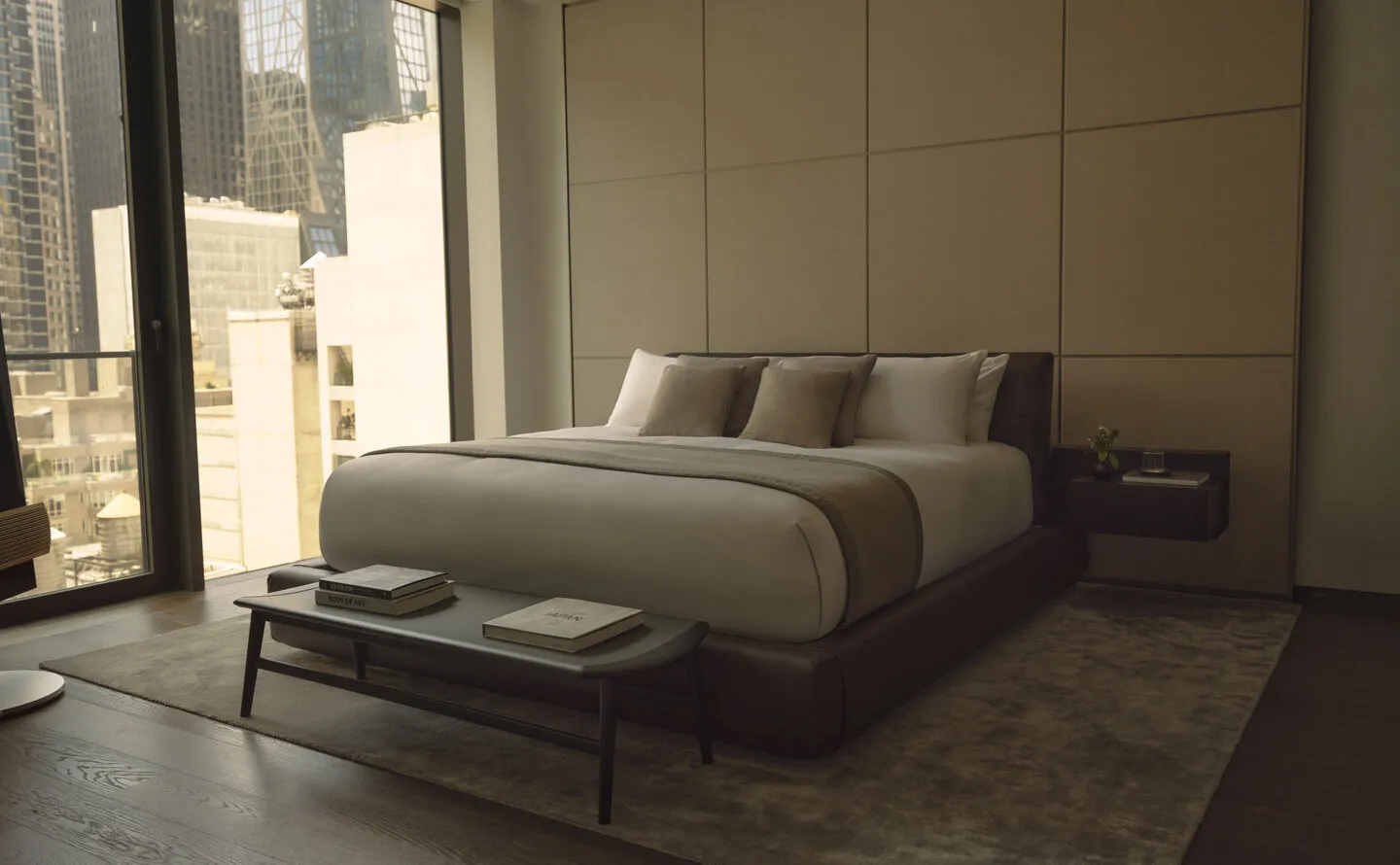 One-bedroom home on the 17th floor at Aman New York, featuring a bed with neutral bedding and floor-to-ceiling windows overlooking the city.