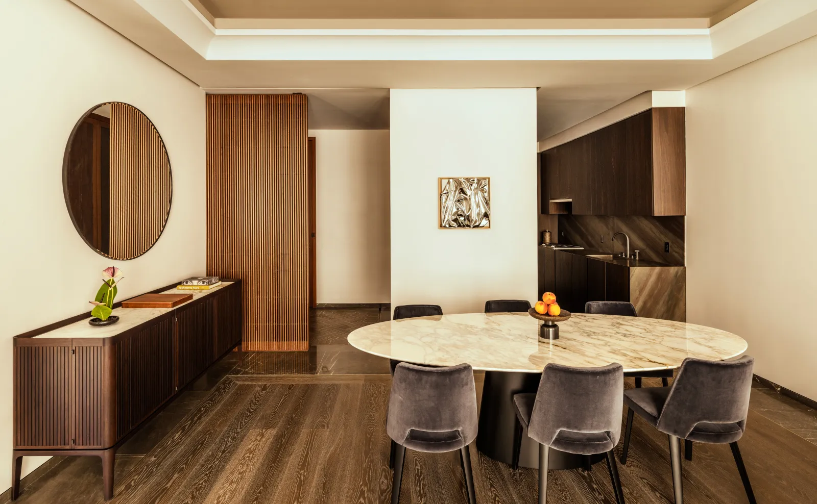 Dining area in a one-bedroom home at Aman New York, featuring a wooden table, upholstered chairs, and warm wood furnishings.
